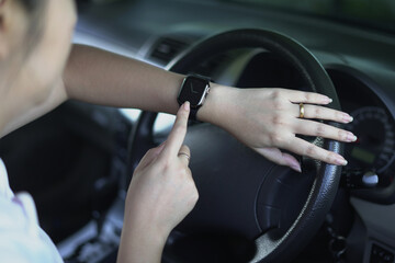 An asian businesswoman getting headache in the middle of traffic, looking at the watch as she is...