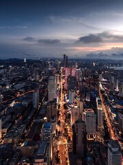 Aerial View of Modern City Skyline at Twilight with Illuminated Streets and Distant Mountains