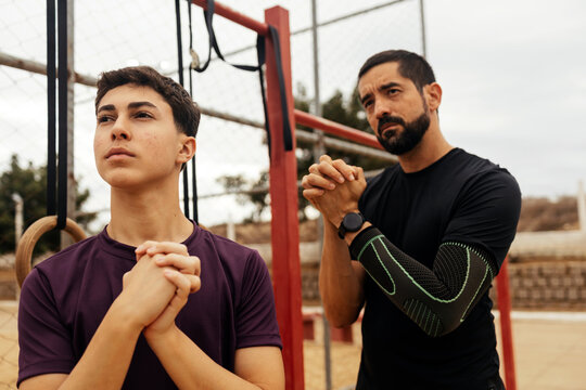 Teenager and adult man warming up before calisthenics workout at outdoor gym
