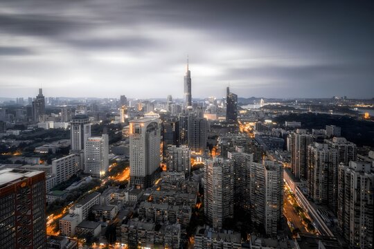 Nanjing City Skyline at Dusk with Illuminated Skyscrapers Under Dramatic Cloudy Sky - Aerial View of Modern Urban Architecture