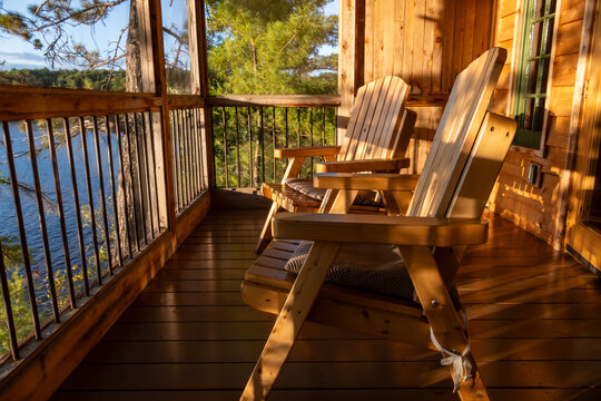 A Couple of Adirondack Chairs in a Covered Porch of a Cottage Overlooking French River in the Late Afternoon Sun
