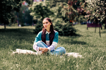 Lovely woman outdoors enjoying a sunny day in the park wearing casual attire surrounded by lush...