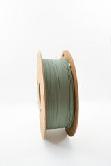 Roll of muted green PLA 3d printer filament on environmental friendly reusable cardboard roll isolated on white background in vertical format