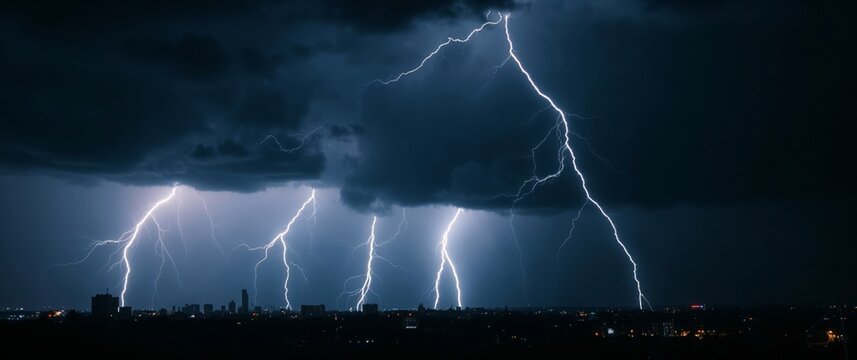 Lightning strikes illuminating night sky over cityscape