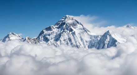 Snowy mountain peak rises above clouds, against a bright blue sky