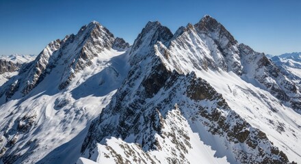 Snowy mountain peaks rise high against clear blue sky in a rugged landscape