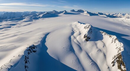 Snowy mountain range under a blue sky, aerial view shows vast icefield