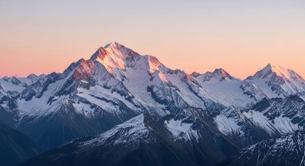 Obraz premium Snowy mountains at dusk, the highest peak catching the golden light