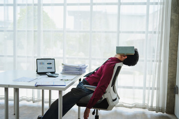 Exhausted businessman sleeping at workplace with book on his face