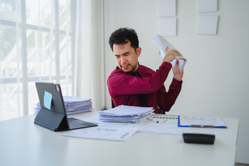 Stressed asian businessman throwing documents in the air in office
