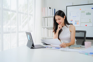 Asian businesswoman reviewing documents at desk in modern office
