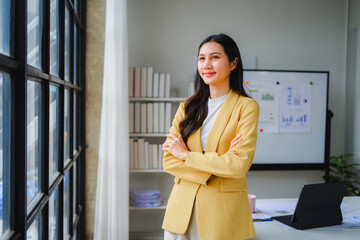 Confident asian businesswoman standing with arms crossed in modern office