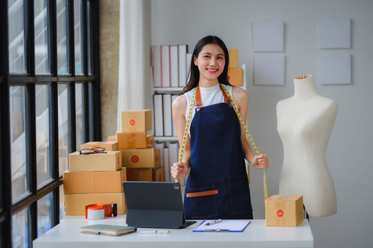 Fashion designer holding measuring tape and smiling in her workshop