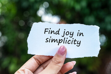 Hand holding a note with inspirational quotes find joy in simplicity