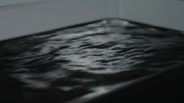 Macro oblique video of anthracite mirror liquid breathing with slow specular ribbons