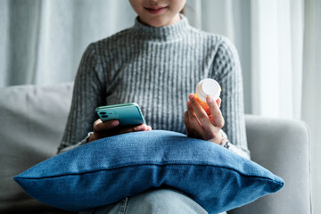 Hand of woman using smartphone for searching online information about prescription pill bottles