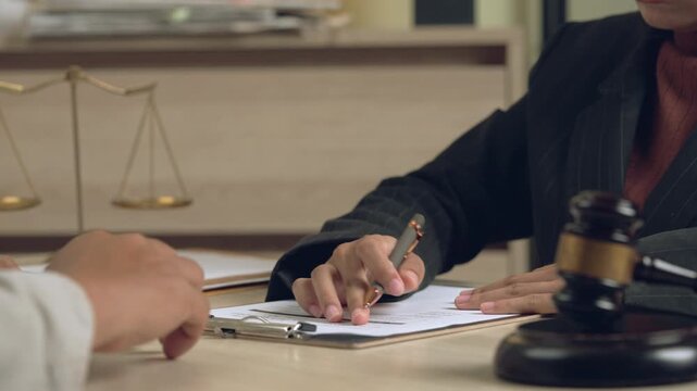 Attorney signing a legal document with justice scale and gavel placed nearby, representing legal responsibility and fairness.