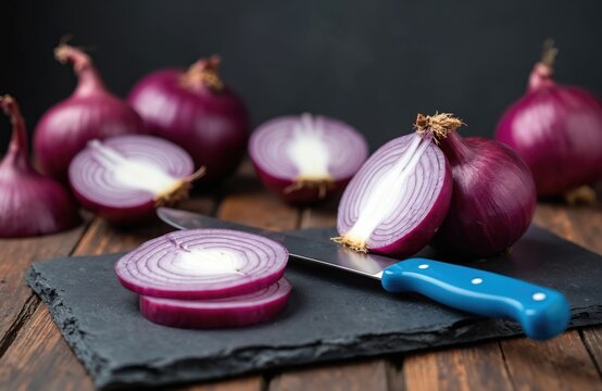 Whole and sliced red onions presented on a dark slate cutting board with a blue handled knife. Focus on the fresh, vibrant purple skin and layered white and purple interior rings.