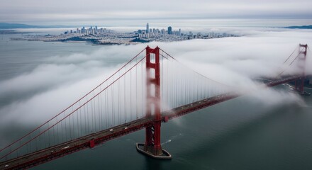 An expansive red suspension bridge spans a waterway its structures partially enveloped by dense fog with a city skyline visible in the hazy background under an overcast sky