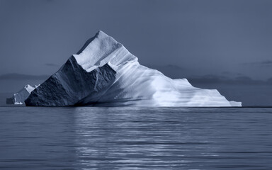 Giant icebergs drifting in the calm blue waters of Hall Bredning, Scoresby Sund, Greenland. Beautiful formations in cool tones, in the cold Arctic waters.