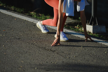 Female athlete preparing for running on asphalt road