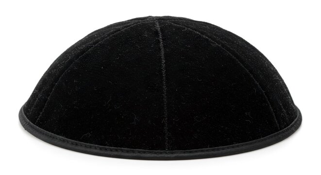 A black rounded kippah with distinct fabric texture and edge trim is isolated on a white background