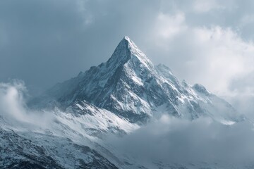 Obraz premium Majestic snow-capped mountain peak piercing a cloudy sky