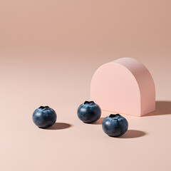 Three fresh blueberries with a geometric shape on a pink pastel background