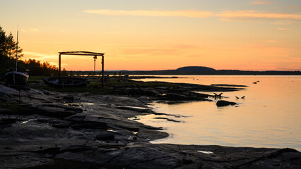Serene sunset over rocky shoreline with calm water reflection in White Sea, Russian Karelia, landscape and northern nature