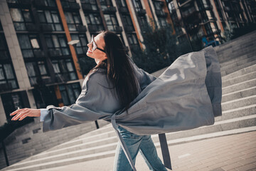 Obraz premium Fashionable young woman in a trench coat enjoying a stylish urban lifestyle outdoors during a breezy day