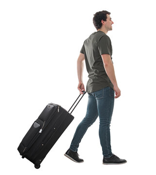 Side view guy traveler carrying his rolling suitcase, walking isolated on transparent background. Full length male tourist with luggage