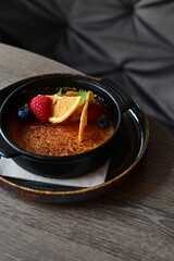 crème brûlée served with fresh fruits on a grey background.