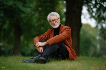 Obraz premium Caucasian elderly male in smart casual attire sitting outdoors in park