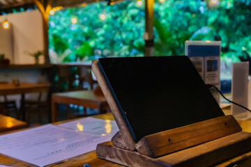 Cozy minimal cafe or coffee shop co-working space with digital tablet white screen mockup stand on a wooden table, close-up image workspace. 3d render, 3d illustration.