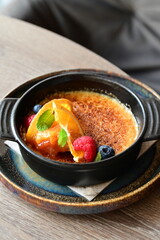 crème brûlée served with fresh fruits on a grey background.