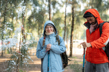 Adventurous Couple Exploring Snowy Forest Trail – Man Pointing While Woman Stands Beside with...