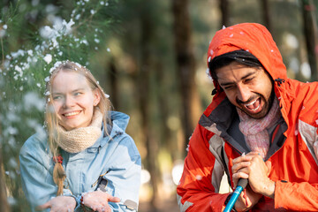 Happy Couple Playing with Snowfall in Winter Forest – Man Gently Touching Woman’s Hood While...
