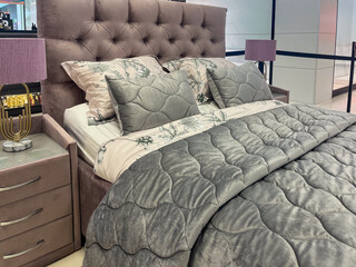 Elegant modern bedroom featuring a plush gray upholstered bed with decorative pillows, cozy quilt, stylish nightstands, and soft lighting creating a serene atmosphere for relaxation