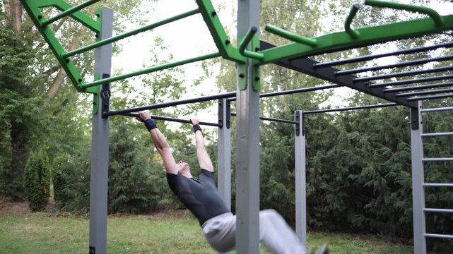 Boy performs front lever holding his body straight and parallel to ground on outdoor pull up bar in park showing impressive strength control and dedication to calisthenics training