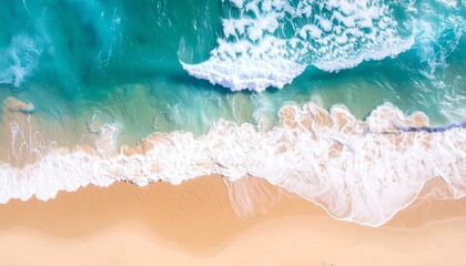 Obraz premium Aerial view reveals vibrant ocean waves crashing onto a sandy shoreline, creating a dynamic contrast of turquoise and beige tones. The foaming water and smooth sand blend nature's beauty seamlessly