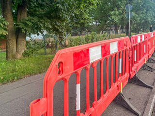 Bright orange traffic barrier with white stripes positioned along a road, indicating construction...