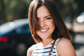 Obraz premium Charming young woman enjoying a sunny day outdoors in a stylish striped shirt
