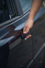 Close-up of a person&rsquo;s hand opening a car door, concept of transport, travel, safety, daily life and mobility.

