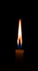 Fototapeta premium A tall single flame burning brightly in the dark, symbolizing hope, light, and spirituality.