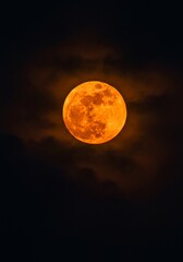 Fiery Orange Full Moon Rising Through Night Clouds