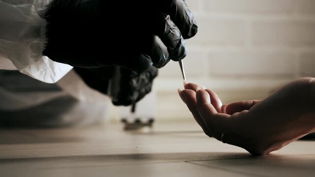 Collecting trace evidence from fingernails using tweezers during forensic examination.