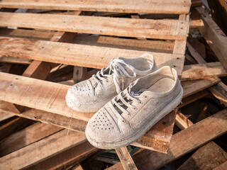 a pair of worn sneakers on a pile of wooden pallets
