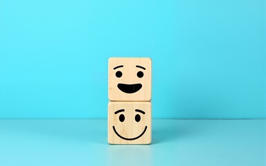 world mental health day concept or feedback rating and positive customer review, wood cube stacking with emotion face icon on blue background. High quality