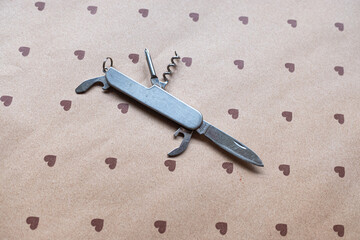Obraz premium A classic metal multi-tool pocket knife on a heart pattern background, Versatile Tool