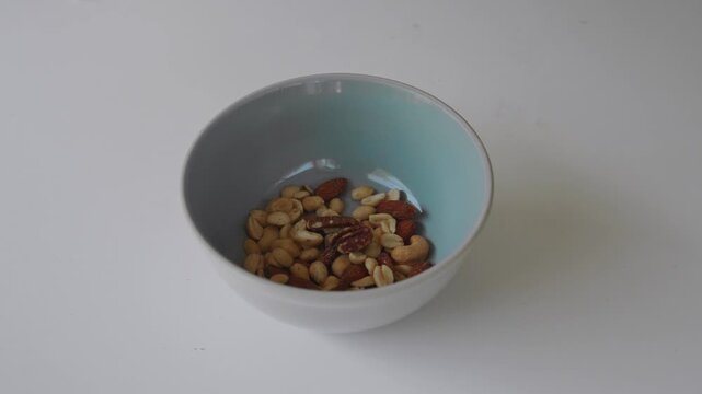 Mixed nuts falling into a bowl on a white background